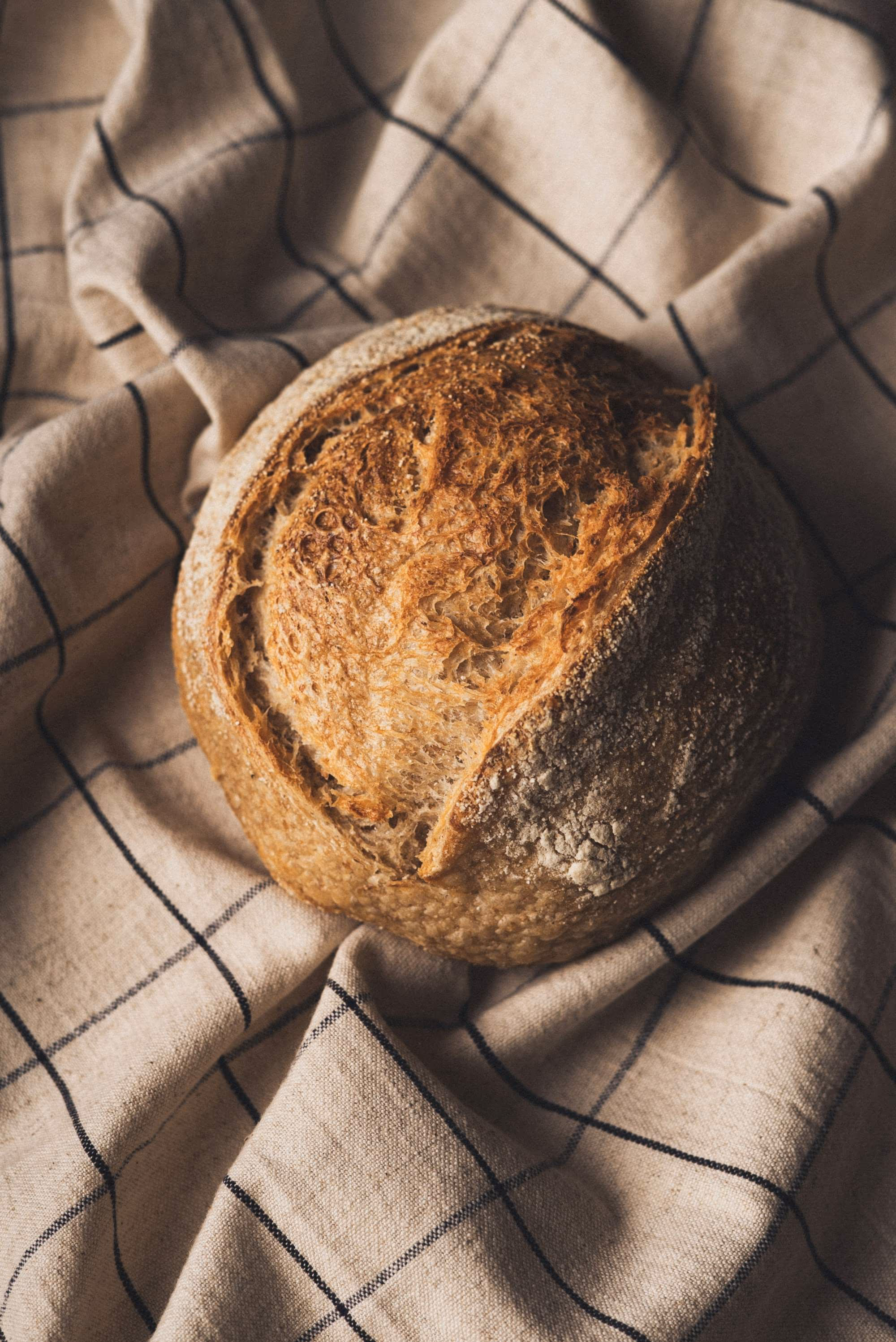 Pain de campagne à la croûte dorée posé sur un torchon de lin écru à carreaux