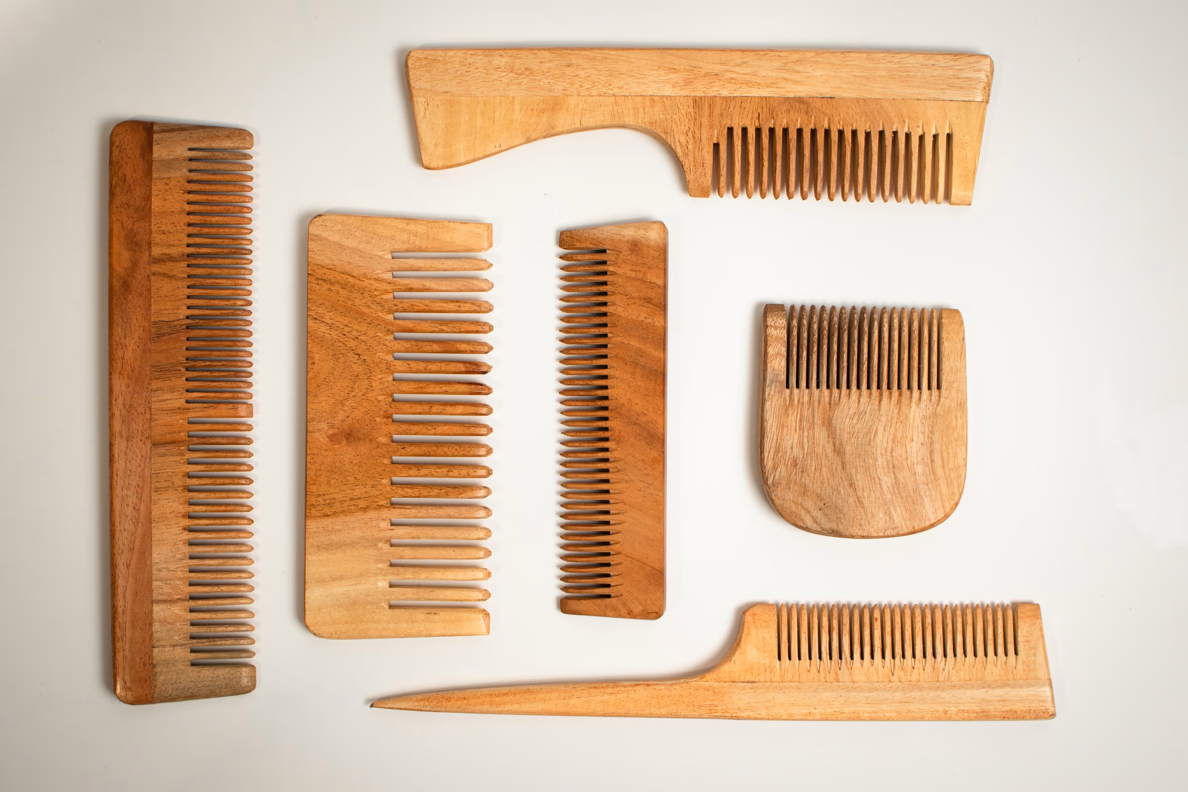 Six peignes en bois de formes différentes disposés sur fond blanc