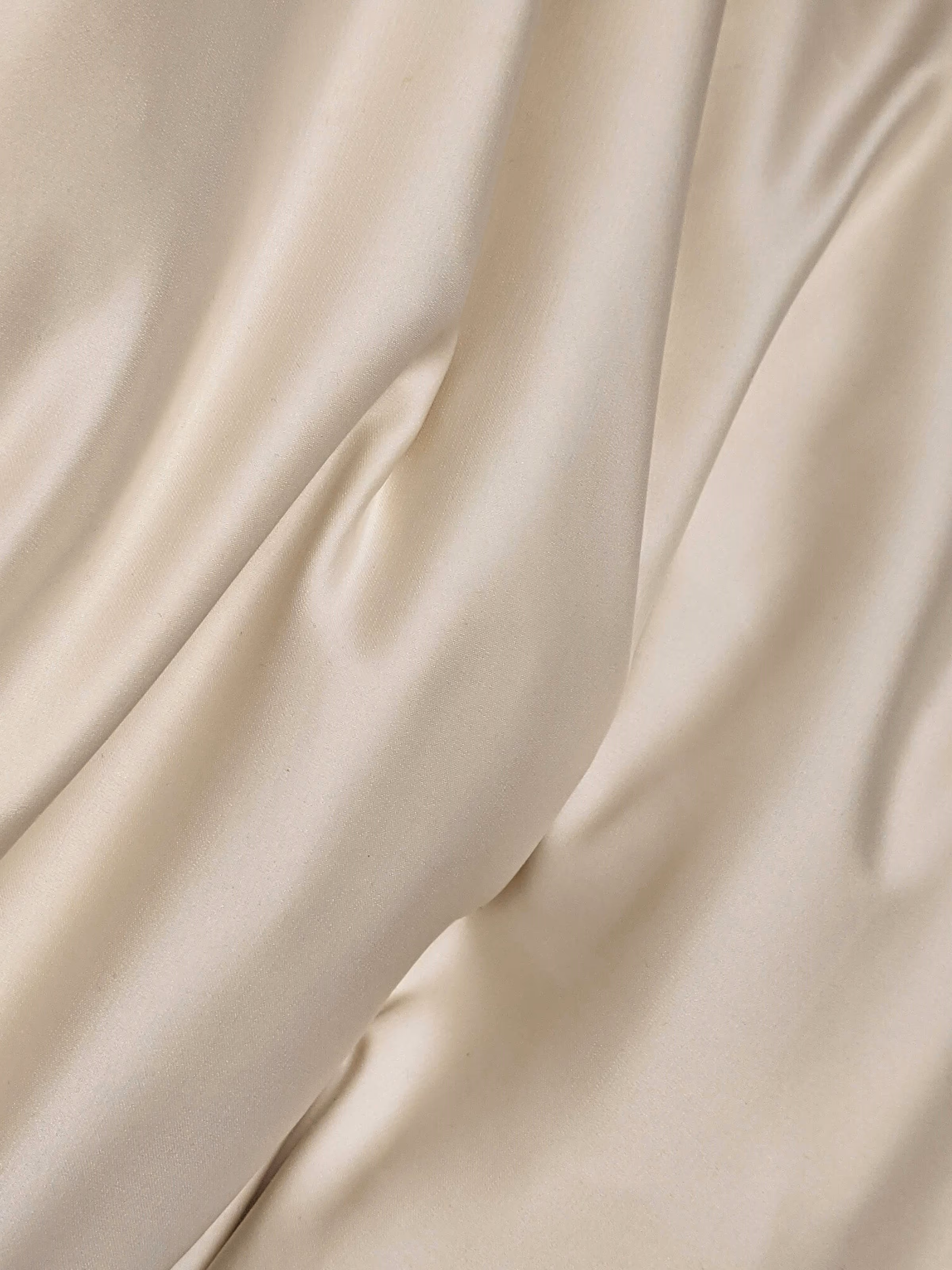 Les plis souples d’un drap de satin crème