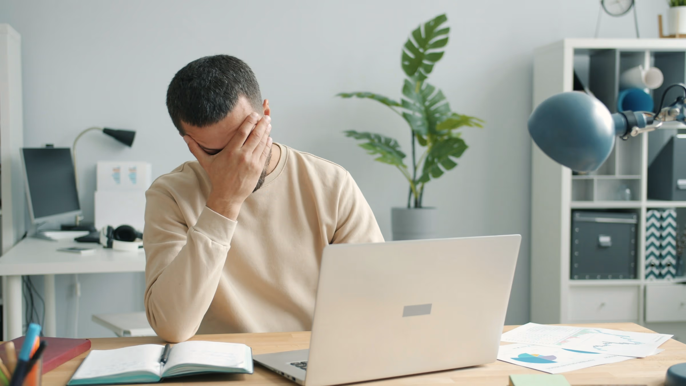 Homme attablé à son bureau, se massant les yeux avec lassitude devant son écran