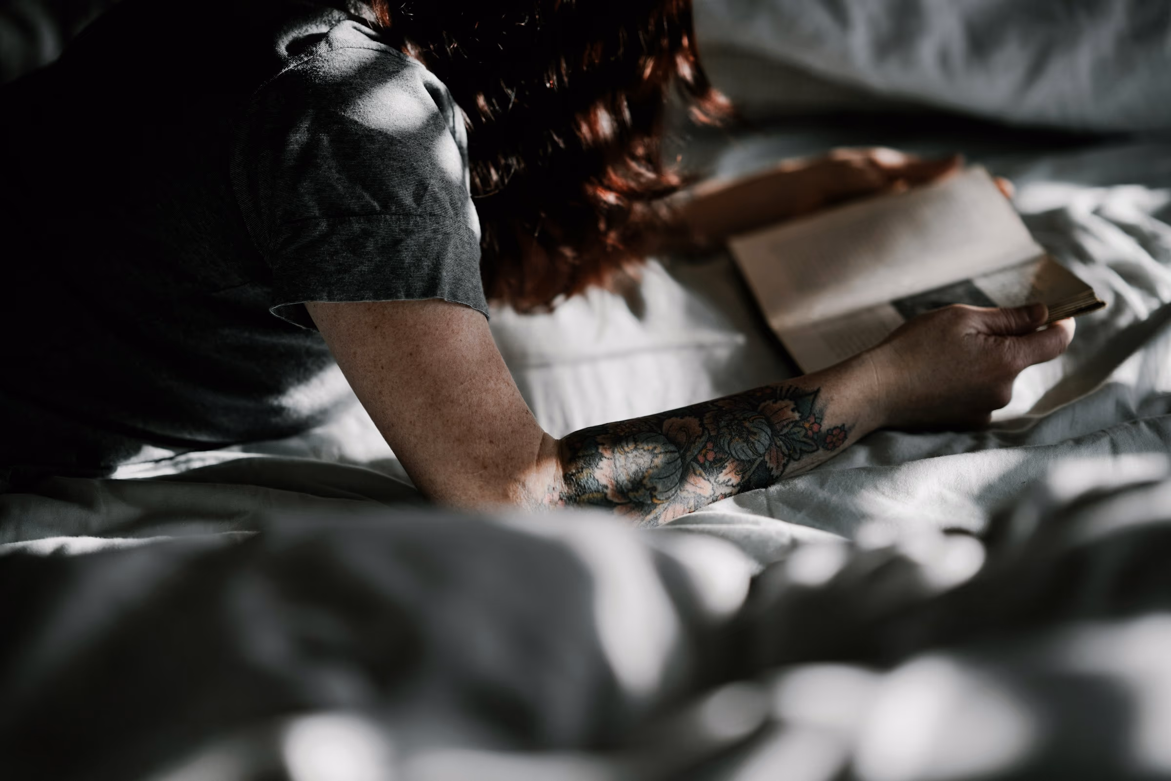 Personne lisant un livre au lit dans une lumière tamisée de fin de soirée