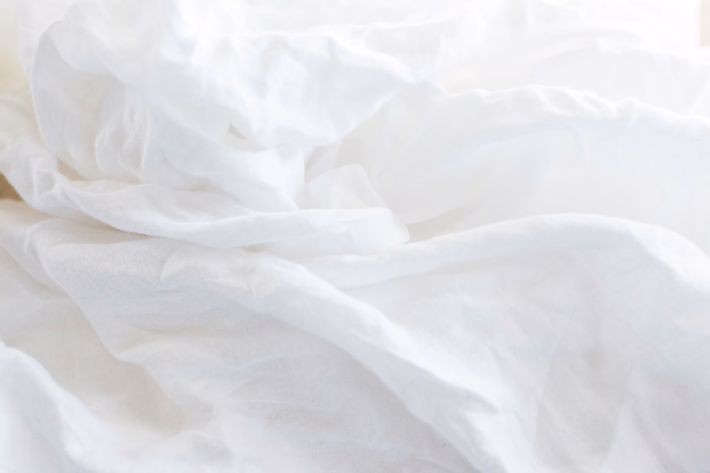 Détail d'un oreiller et de draps clairs sur un lit soigneusement préparé