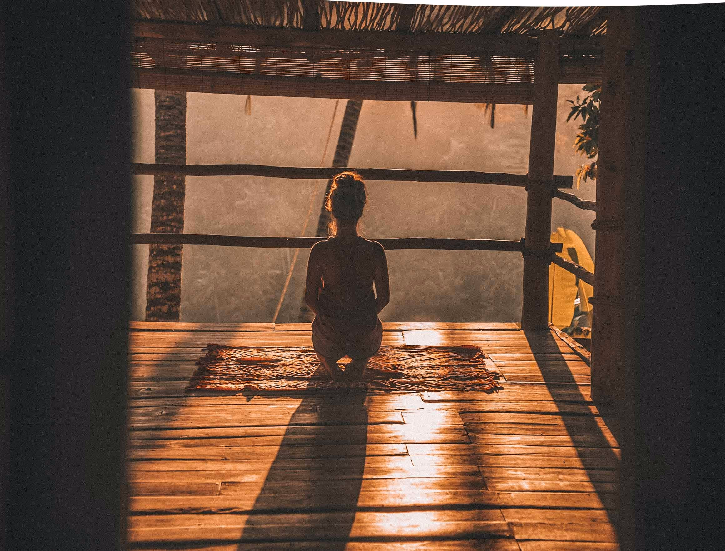Personne assise paisiblement près d'une fenêtre, les yeux clos, dans la lumière douce d'une fin de journée