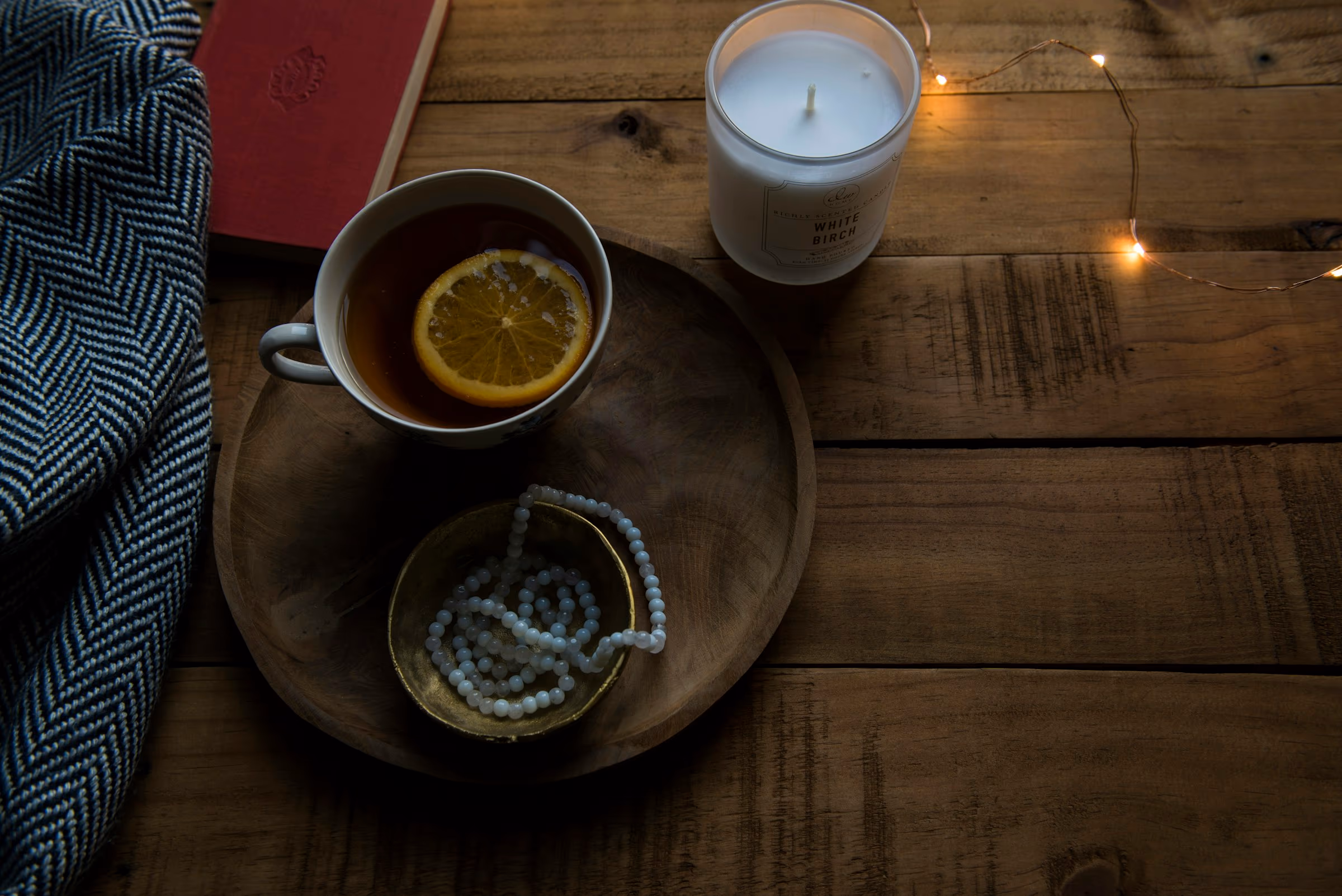 Tasse de tisane fumante posée près d'un livre dans une lumière tamisée de fin de soirée