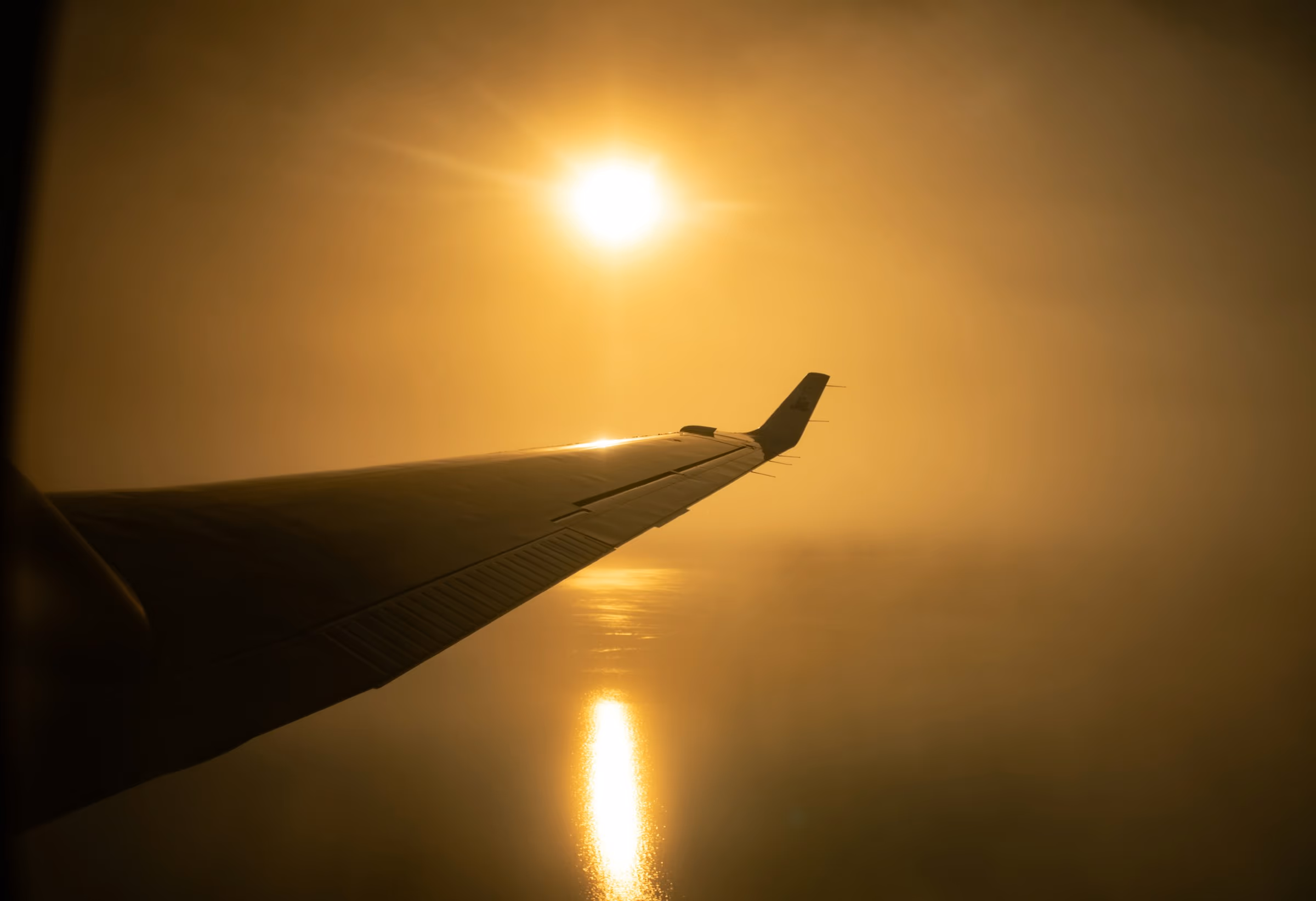 Vue par le hublot d'un avion au-dessus d'une mer de nuages au lever du jour